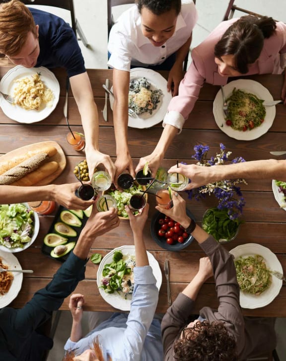 a group of people sitting around a table eating food and drinking beer