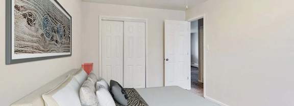 A bedroom with a bed, pillows, a ceiling fan, and a painting on the wall.