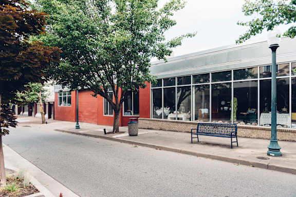 A bench is on the sidewalk in front of a building.