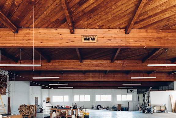 A large warehouse with a wooden ceiling and a sign that reads "AMFAB".