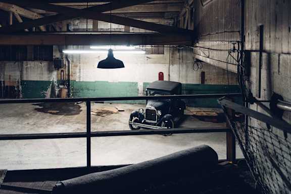 A black car is parked in a dimly lit garage.