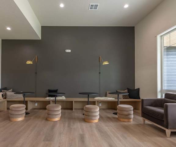 A living room with a grey couch, a wooden table, and a large painting on the wall at Marcola Apartment Homes, Forest Grove
