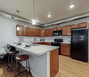 A kitchen with white cabinets and a bar area with stools at Melbourne Apartments, Des Moines, IA