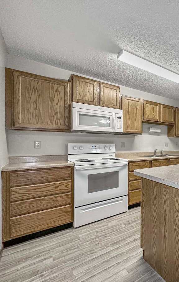 a kitchen with white appliances and wooden cabinets at Creekstone Falls, Sioux Falls, SD