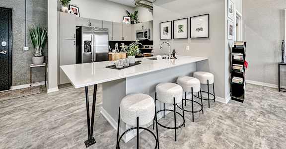 A kitchen with a white counter and bar stools.at Level, Des Moines