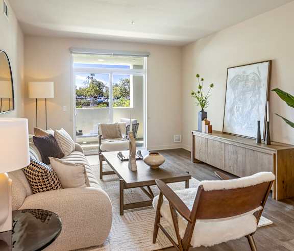 A living room with a white couch, a wooden coffee table, and a large window. at Casa Mira View Apartments, San Diego, CA 92126