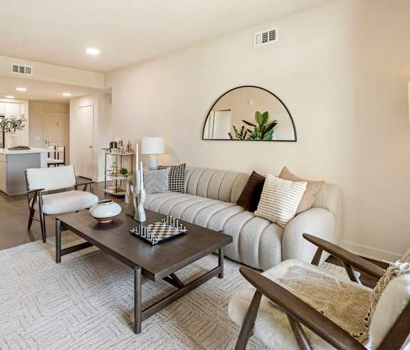 A modern living room with a white sofa, a wooden coffee table, and a mirror on the wall. at Casa Mira View Apartments, San Diego, CA 92126