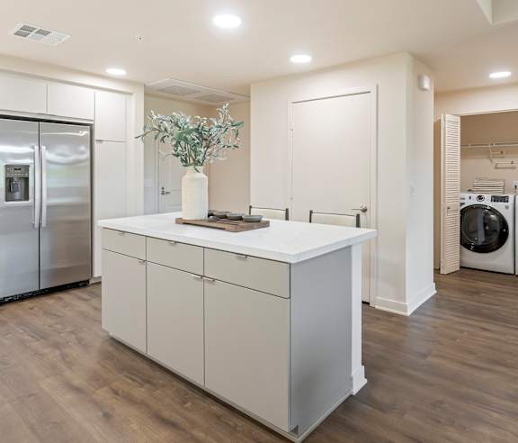 A modern kitchen with a white island and stainless steel appliances. at Casa Mira View Apartments, San Diego, CA 92126