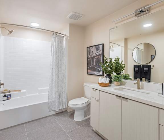 A bathroom with a white toilet, a white sink, and a white bathtub with a white shower curtain. at Casa Mira View Apartments, San Diego, CA 92126
