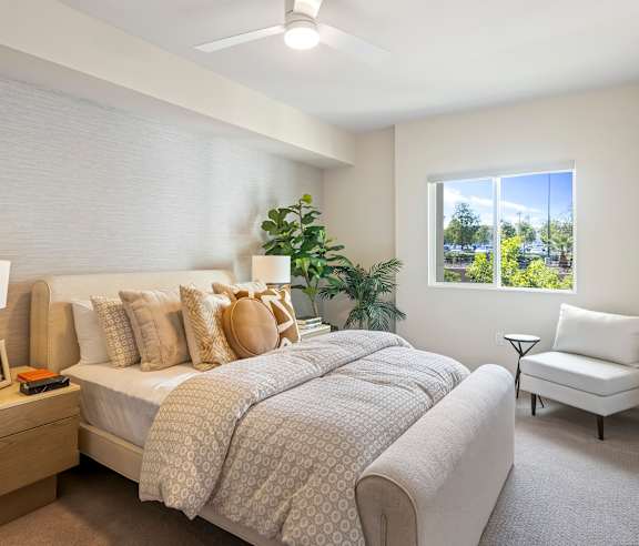 A bedroom with a large bed and a window overlooking a green landscape. at Casa Mira View Apartments, San Diego, CA 92126