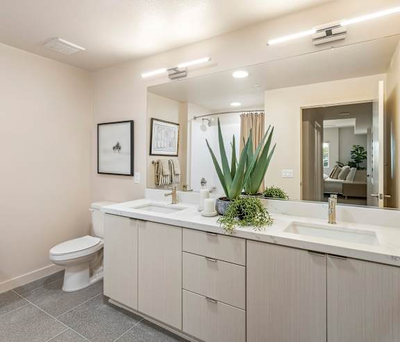 A bathroom with a white toilet and a large mirror above a sink. at Casa Mira View Apartments, San Diego, CA 92126