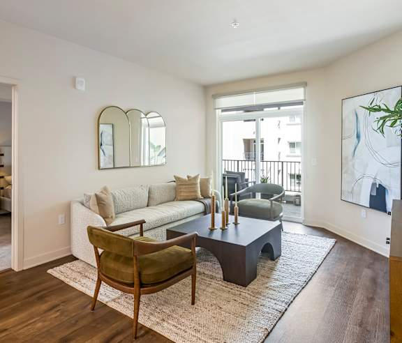 A living room with a white couch, a wooden chair, and a coffee table. at Casa Mira View Apartments, San Diego, CA 92126