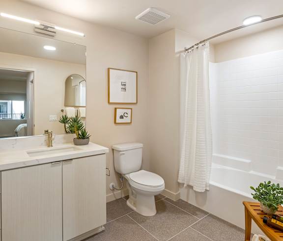 A white bathroom with a toilet, sink, and mirror. at Casa Mira View Apartments, San Diego, CA 92126