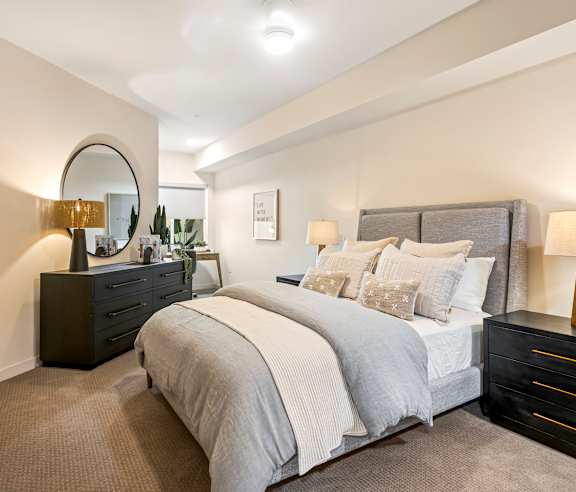 A bedroom with a large bed, a dresser, and a mirror. at Casa Mira View Apartments, San Diego, CA 92126