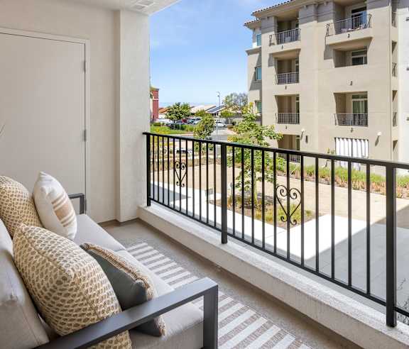 A balcony with a black railing and a couch with pillows. at Casa Mira View Apartments, San Diego, CA 92126
