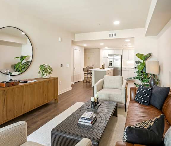 A modern living room with a brown leather couch and a wooden sideboard. at Casa Mira View Apartments, San Diego, CA 92126