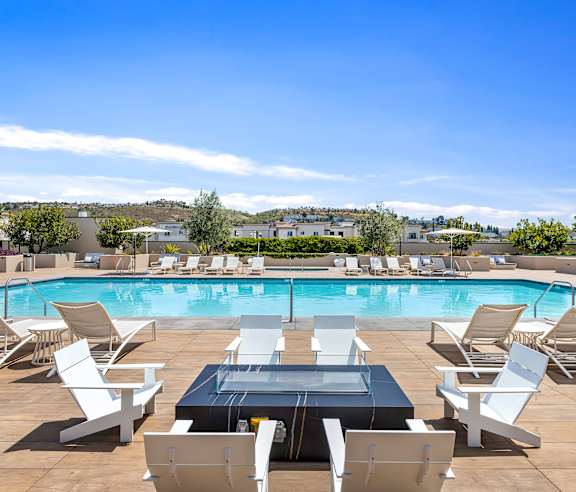 A poolside area with chairs and a table. at Casa Mira View Apartments, San Diego, CA 92126
