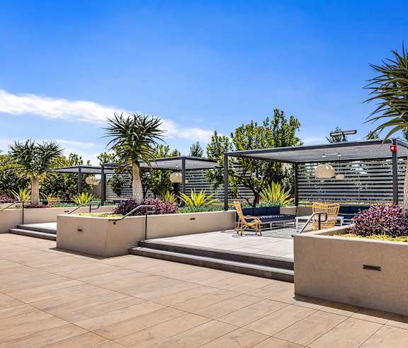 A modern outdoor seating area with concrete planters and wooden chairs. at Casa Mira View Apartments, San Diego, CA 92126