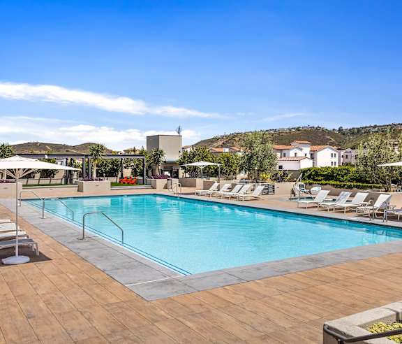 A large swimming pool with a wooden deck and sun loungers. at Casa Mira View Apartments, San Diego, CA 92126