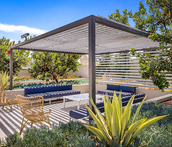 A patio with a blue couch and a wicker chair under a white canopy. at Casa Mira View Apartments, San Diego, CA 92126