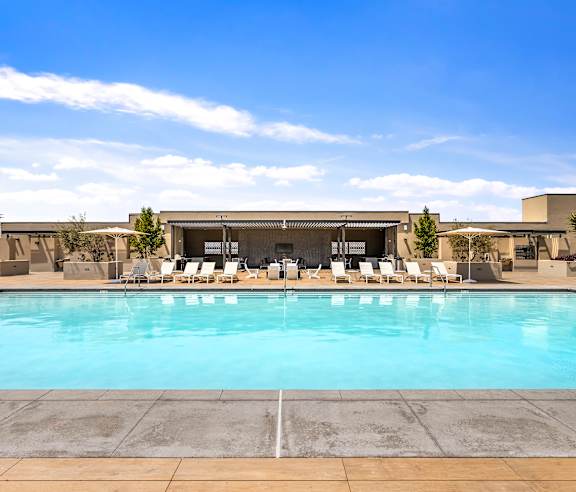 A pool with chairs and a building in the background. at Casa Mira View Apartments, San Diego, CA 92126