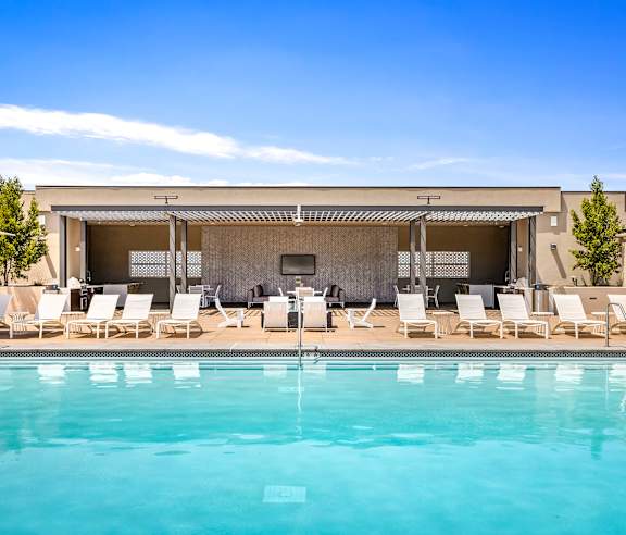 A pool with chairs and a building in the background. at Casa Mira View Apartments, San Diego, CA 92126