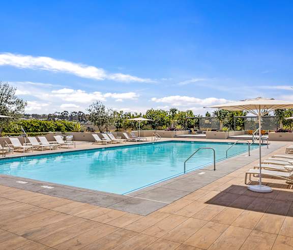 A large outdoor swimming pool surrounded by sun loungers and umbrellas. at Casa Mira View Apartments, San Diego, CA 92126