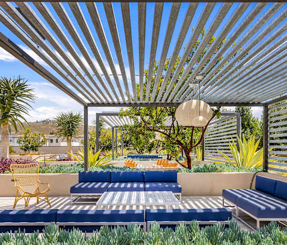 A patio with a blue couch and a yellow chair under a striped awning. at Casa Mira View Apartments, San Diego, CA 92126