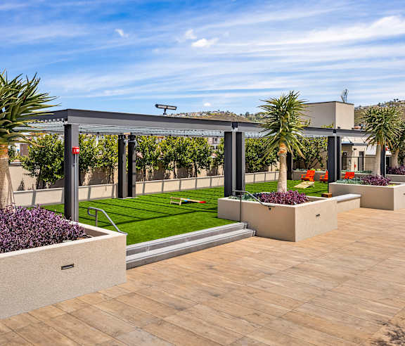A modern outdoor patio area with a metal pergola and concrete planters. at Casa Mira View Apartments, San Diego, CA 92126