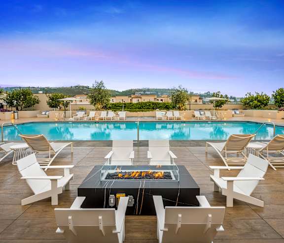 A fire pit is surrounded by white chairs on a patio. at Casa Mira View Apartments, San Diego, CA 92126