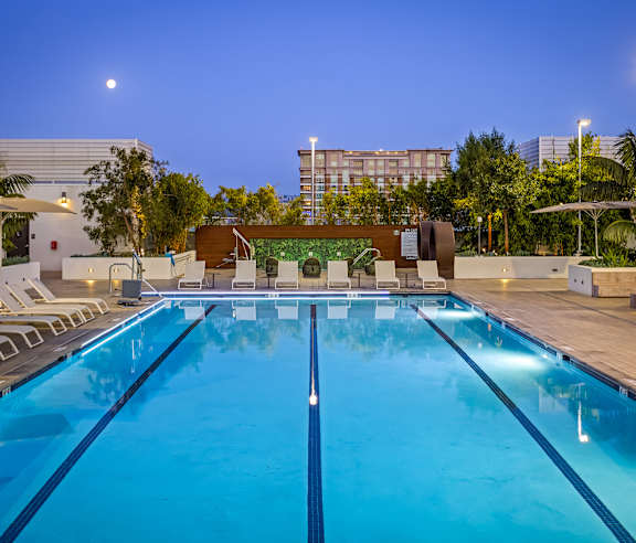 A large swimming pool with lounge chairs and a building in the background. at Elements Apartments, Irvine, CA