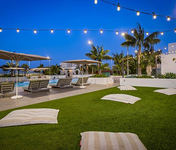 A poolside area with lounge chairs and umbrellas. at Elements Apartments, Irvine, CA