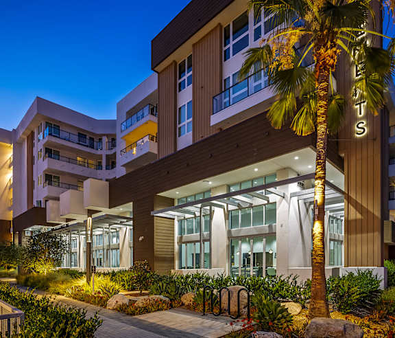 A modern building with a palm tree in front of it. at Elements Apartments, Irvine, CA