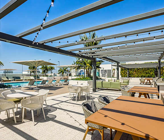 A sunny day at the outdoor seating area of a restaurant with tables and chairs. at Elements Apartments, Irvine, CA
