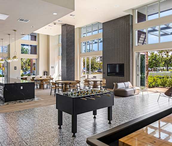 A foosball table is in the middle of a room with a lot of windows. at Elements Apartments, Irvine, CA