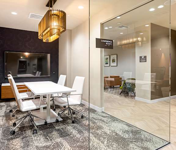 A conference room with a glass door and a white table with chairs. at Elements Apartments, Irvine, CA