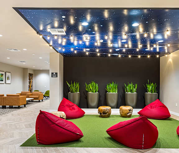 A room with a black wall and a ceiling with lights and plants. at Elements Apartments, Irvine, CA