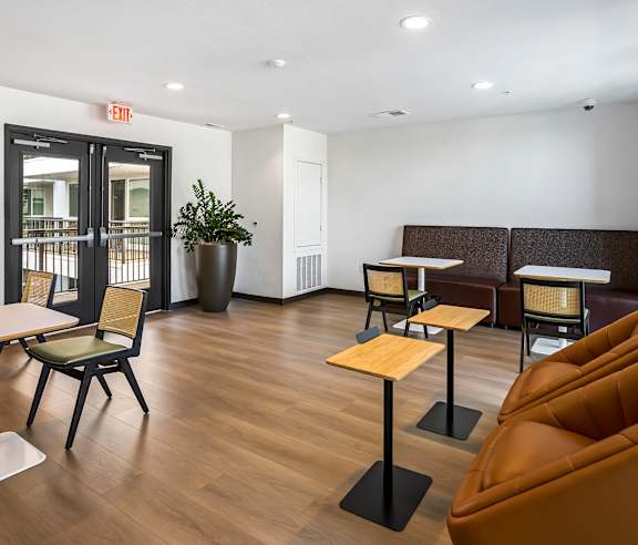 A room with a brown leather couch, a wooden table and a black chair. at Elements Apartments, Irvine, CA