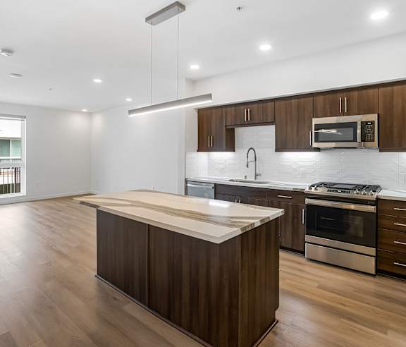 A modern kitchen with wooden cabinets and stainless steel appliances. at Elements Apartments, Irvine, CA