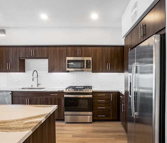 A modern kitchen with dark wood cabinets and stainless steel appliances. at Elements Apartments, Irvine, CA