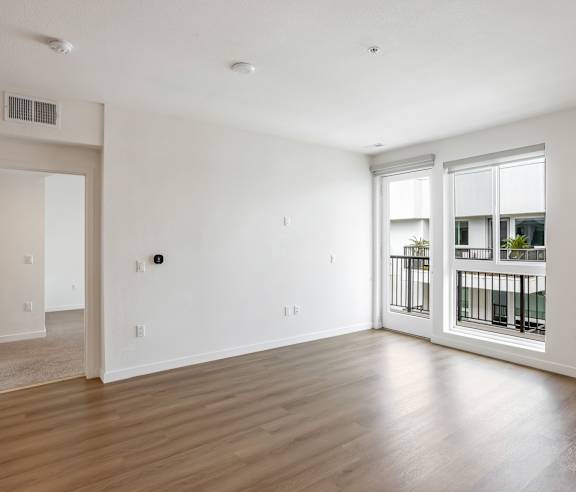 A spacious room with wooden floors and a large window. at Elements Apartments, Irvine, CA