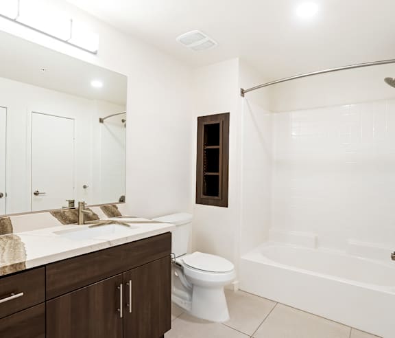A white bathroom with a toilet, sink, and bathtub. at Elements Apartments, Irvine, CA