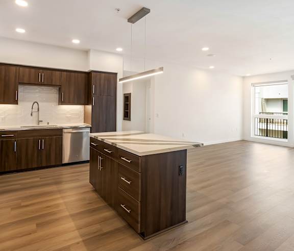 A modern kitchen with wooden cabinets and a large island at Elements Apartments, Irvine, CA