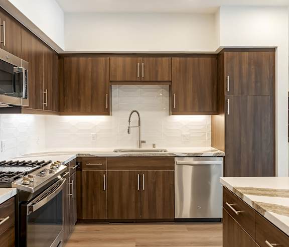 A modern kitchen with dark wood cabinets and stainless steel appliances. at Elements Apartments, Irvine, CA