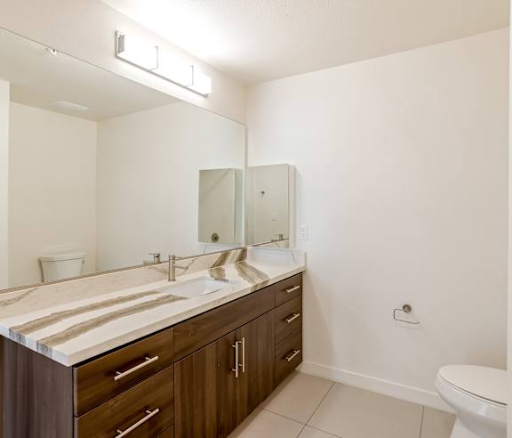 A bathroom with a marble counter top and a white toilet at Elements Apartments, Irvine, CA