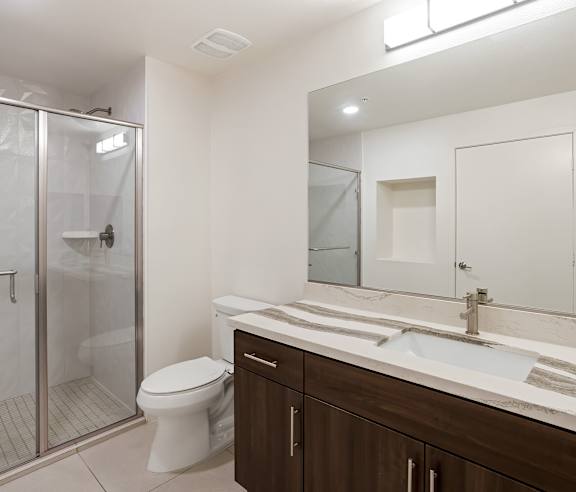 A modern bathroom with a toilet, sink, and shower at Elements Apartments, Irvine, CA