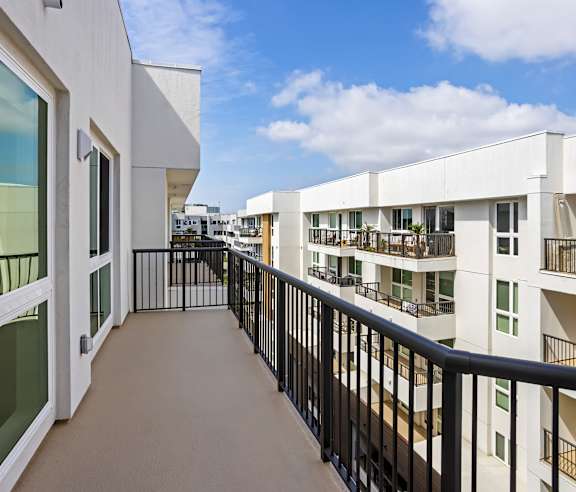 A balcony with black railings and white buildings in the background. at Elements Apartments, Irvine, CA