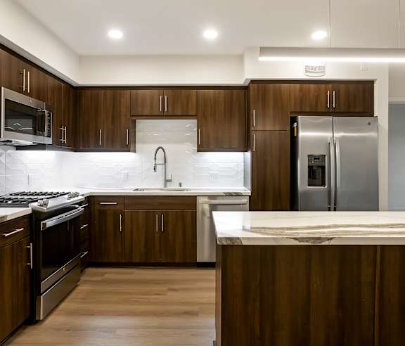 A modern kitchen with dark wood cabinets and stainless steel appliances at Elements Apartments, Irvine, CA