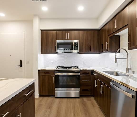 A modern kitchen with dark wood cabinets and stainless steel appliances at Elements Apartments, Irvine, CA