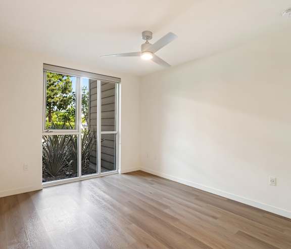 A room with a sliding glass door leading to a garden. at Elements Apartments, Irvine, CA